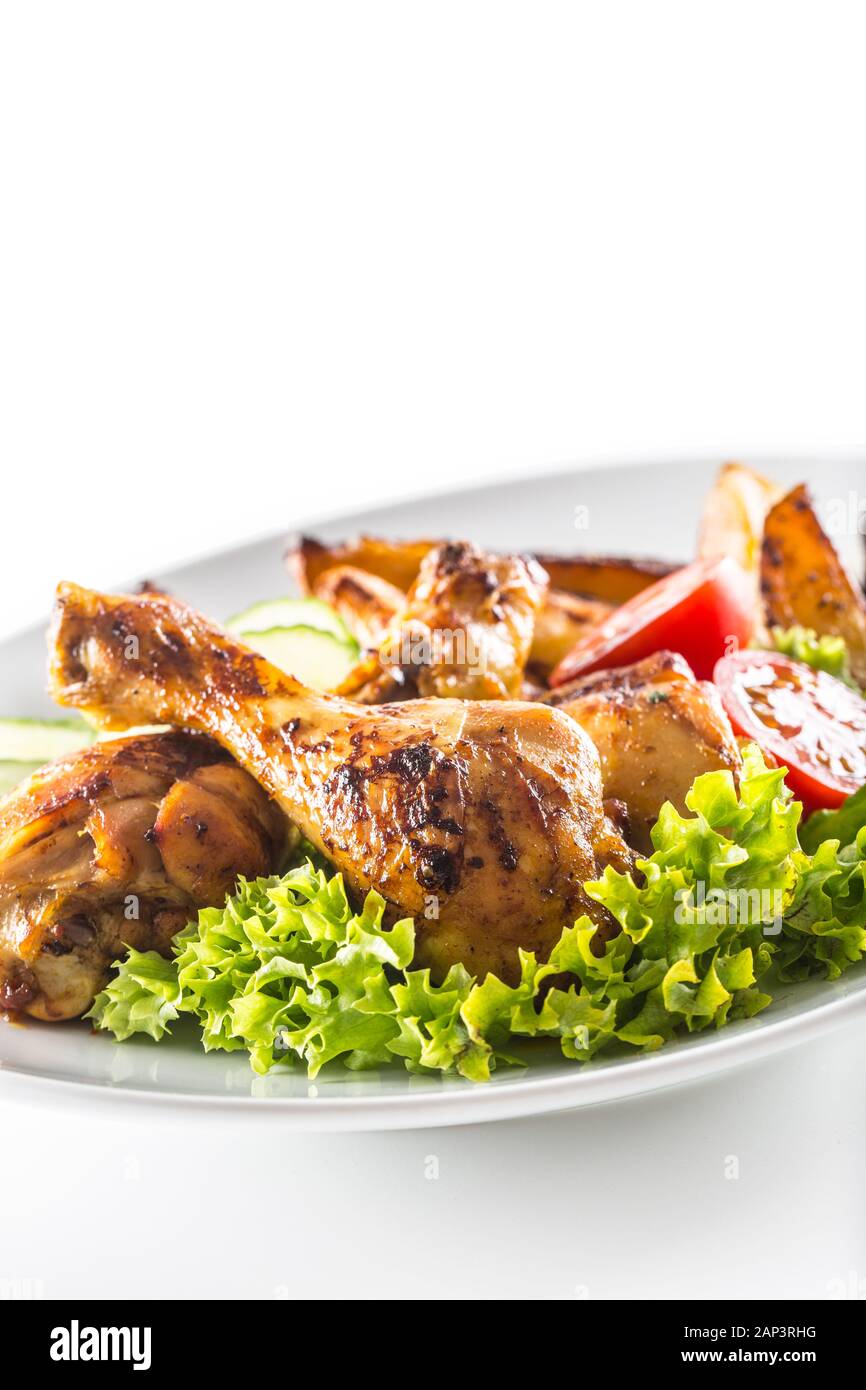 Roasted chicken legs with lettuce salad potatoes and tomatoes isolated on white Stock Photo