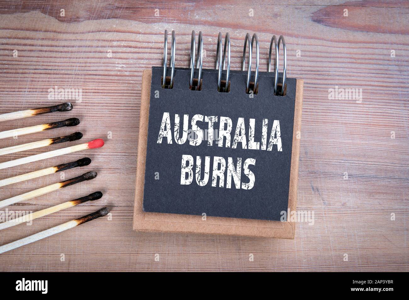 Australia burns. Fire safety, nature, housing and human behavior concept. Burned matches on wood texture background Stock Photo