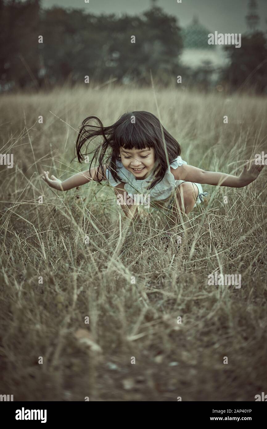 Pretty Little girl in white dress in field at sunset Stock Photo - Alamy