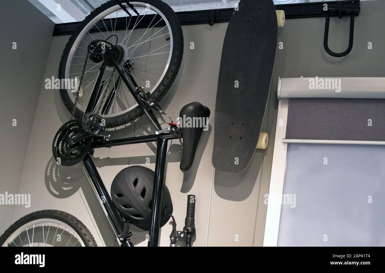 Mountain bike, skateboard, and U Lock hanging from a room wall with special organization attachments. Stock Photo