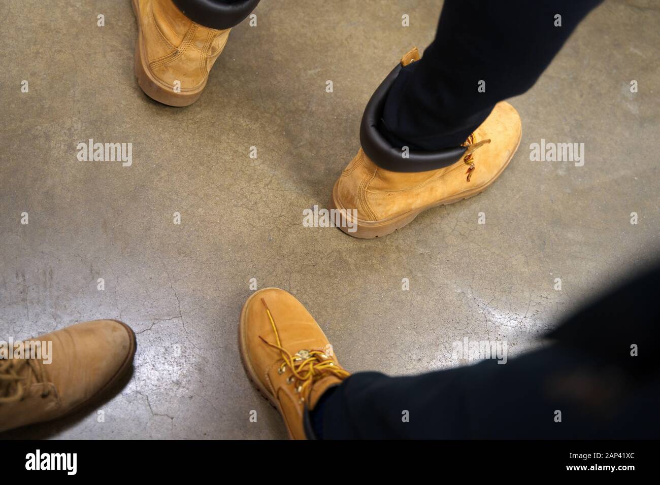 Feet of people with all the same outdoor leather shoes waiting in line. Stock Photo