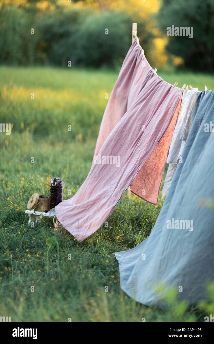 Pink and blue bedding sheet on forest background under the bright warm sun. Clean bed sheet hanging on clothesline at backyard. Hygiene sleeping ware concept. Stock Photo