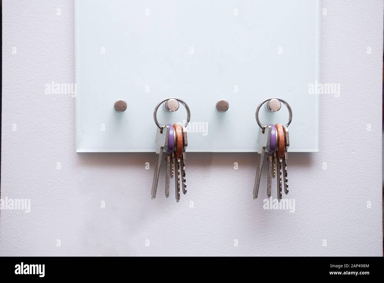 Keys hanging on modern open key box for storage keys on white wall Stock Photo