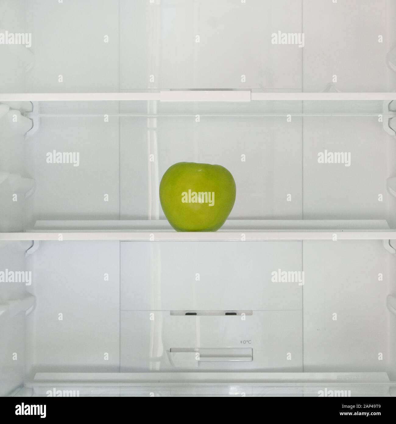 Green ripe apple on the shelf in the fridge. Health starvation, lose weight. Raw diet, starving concept. Stock Photo