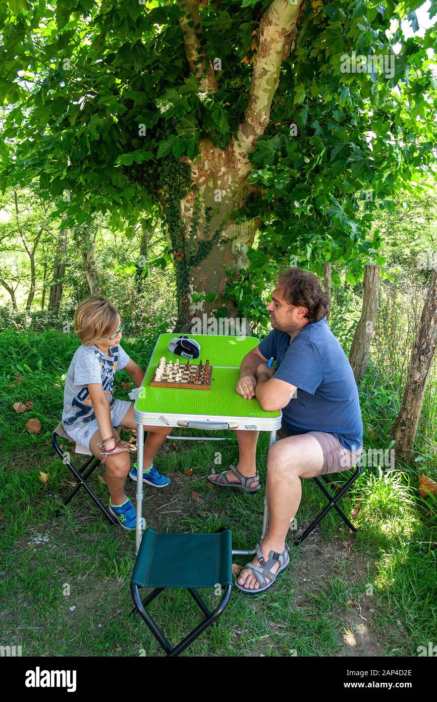 father and son playing chess outdoors Stock Photo