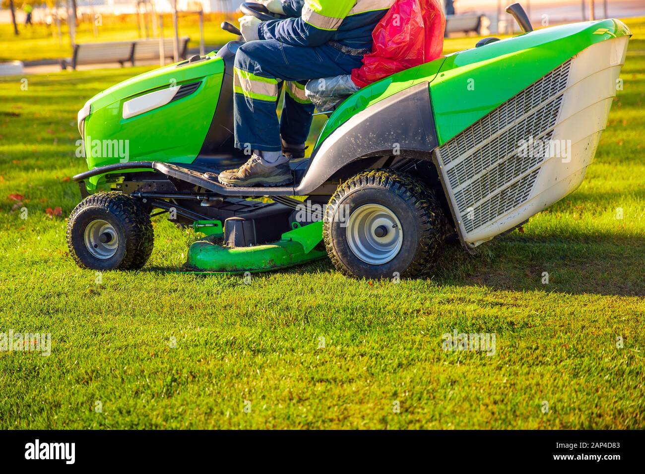 Gardener worker on lawn mower tractor cuts green grass Stock Photo Alamy