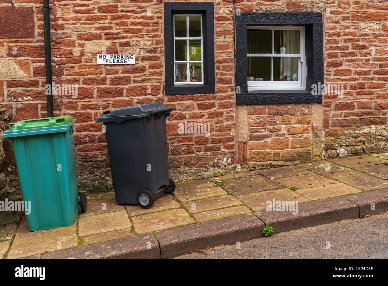 Garbage Cans in front of a house with a sign No Parking Please Stock