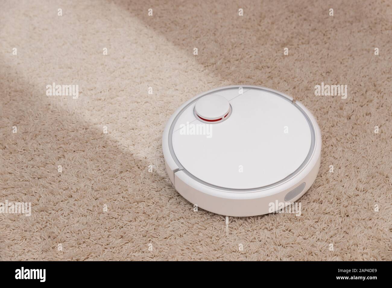 Robotic wireless smart vacuum cleaner working on white with pile carpet