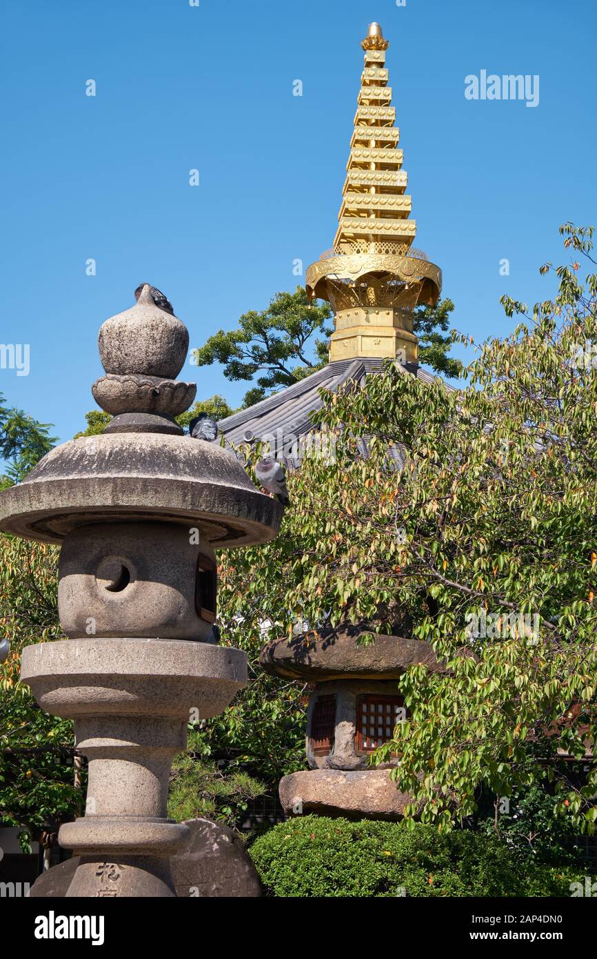 The view of the traditional stone lanterns (Tachidoro) with pagoda tip  (sorin) on the background in the Isshin-ji Temple. Osaka. Japan Stock Photo
