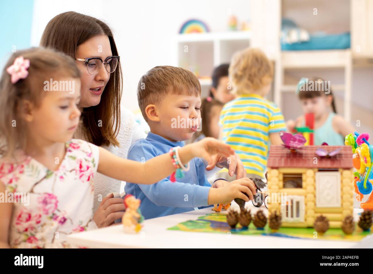 Kids play toys in kindergarten. Group of preschool kids with teacher on lesson in class Stock Photo