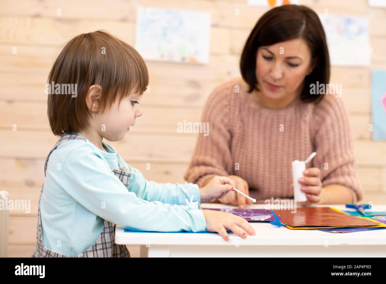 Female teacher play teaches preschooler child in day care center Stock Photo