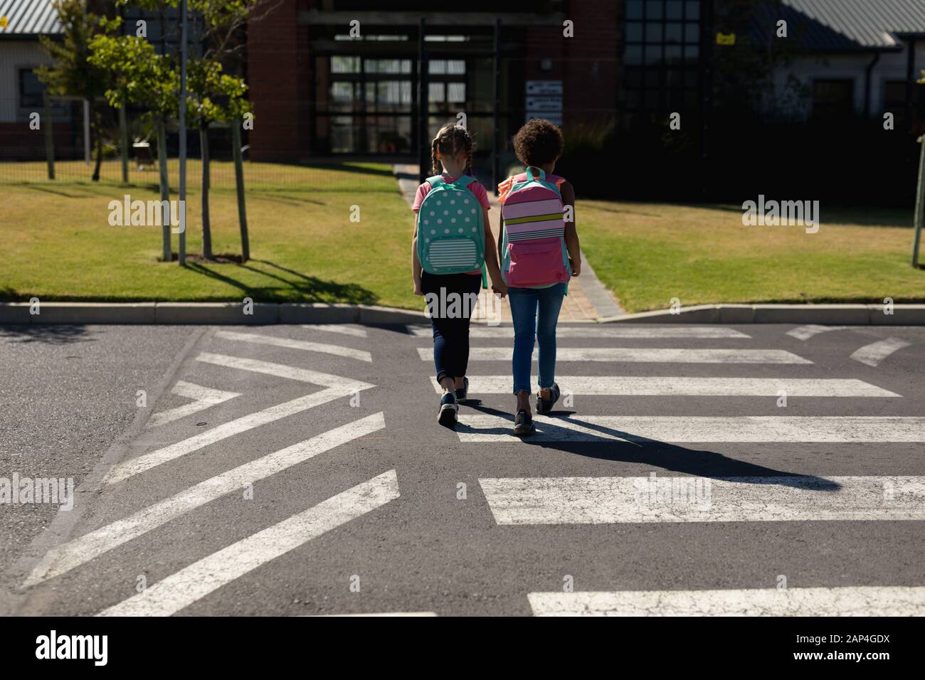 Two schoolgirls crossing the road on a pedestrian crossing Stock Photo ...