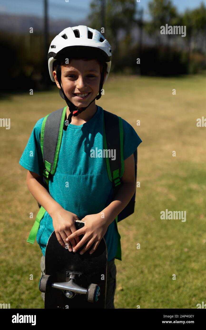 Schoolboy wearing a cycling helmet and holding a skateboard Stock Photo