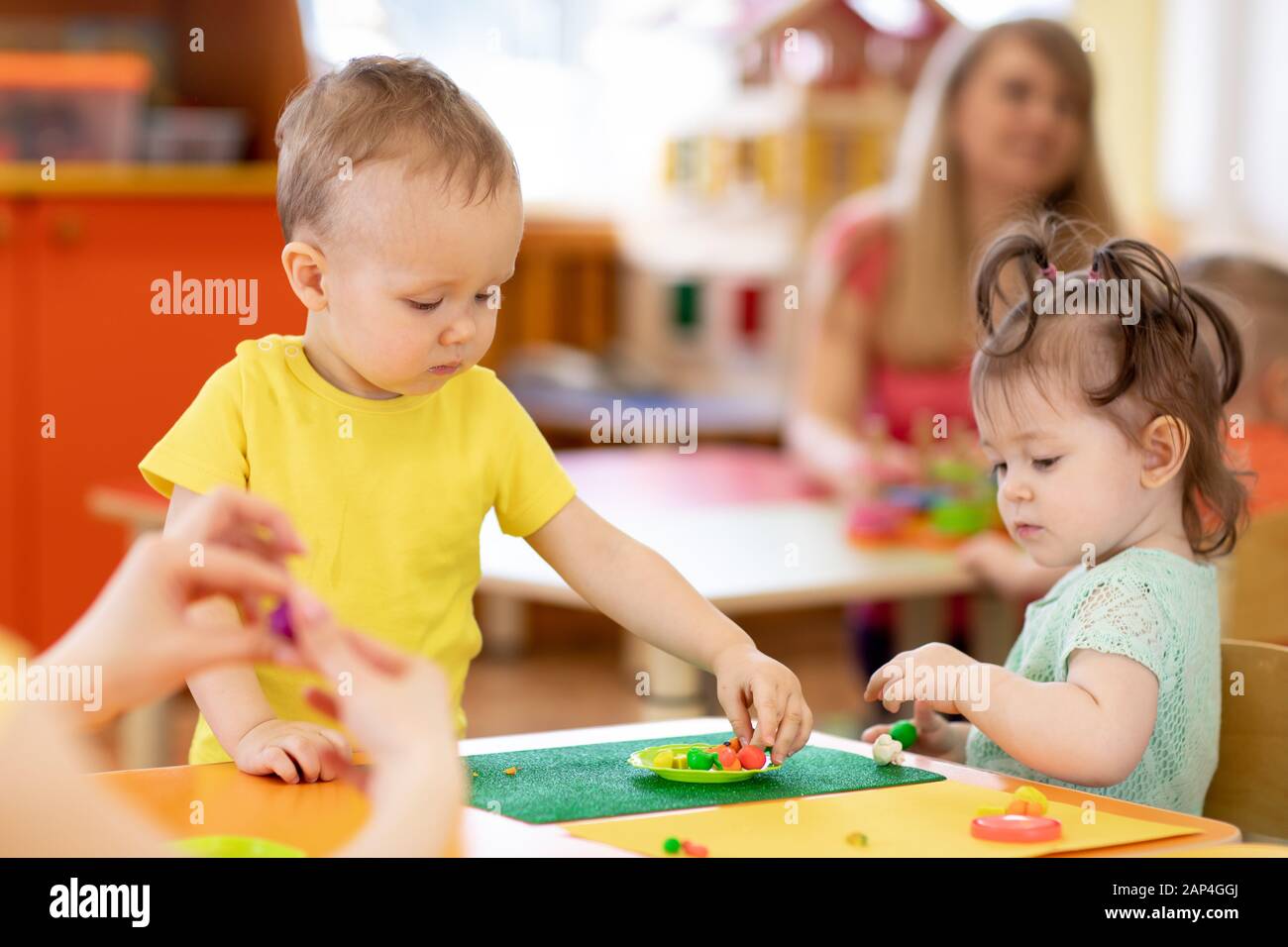 children toddlers playing clay in nursery or daycare or kindergarten Stock Photo