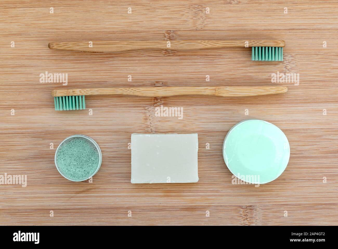 Zero waste bathroom basics. Bamboo toothbrushes,  solid toothpaste in metal tin, solid shampoo and soap on wood background. Plastic free, environment Stock Photo