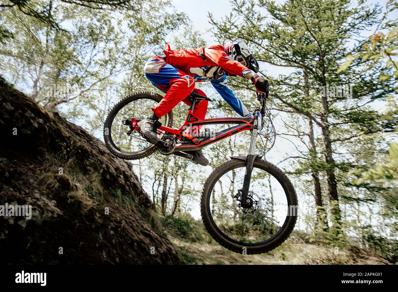 rider jump mountain in forest trail competition downhill Stock Photo