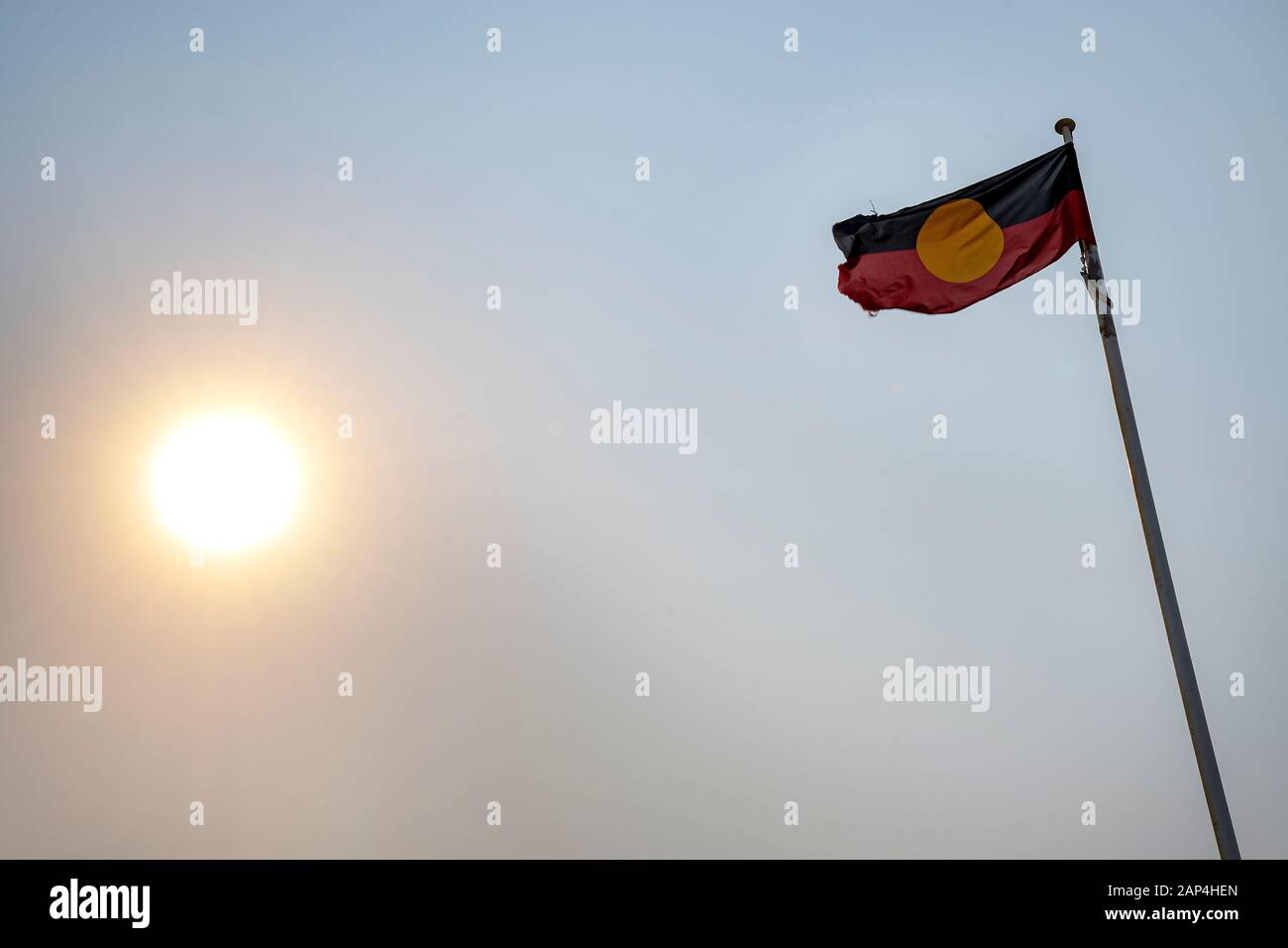 Aboriginal flag flying against sky with low sun Stock Photo