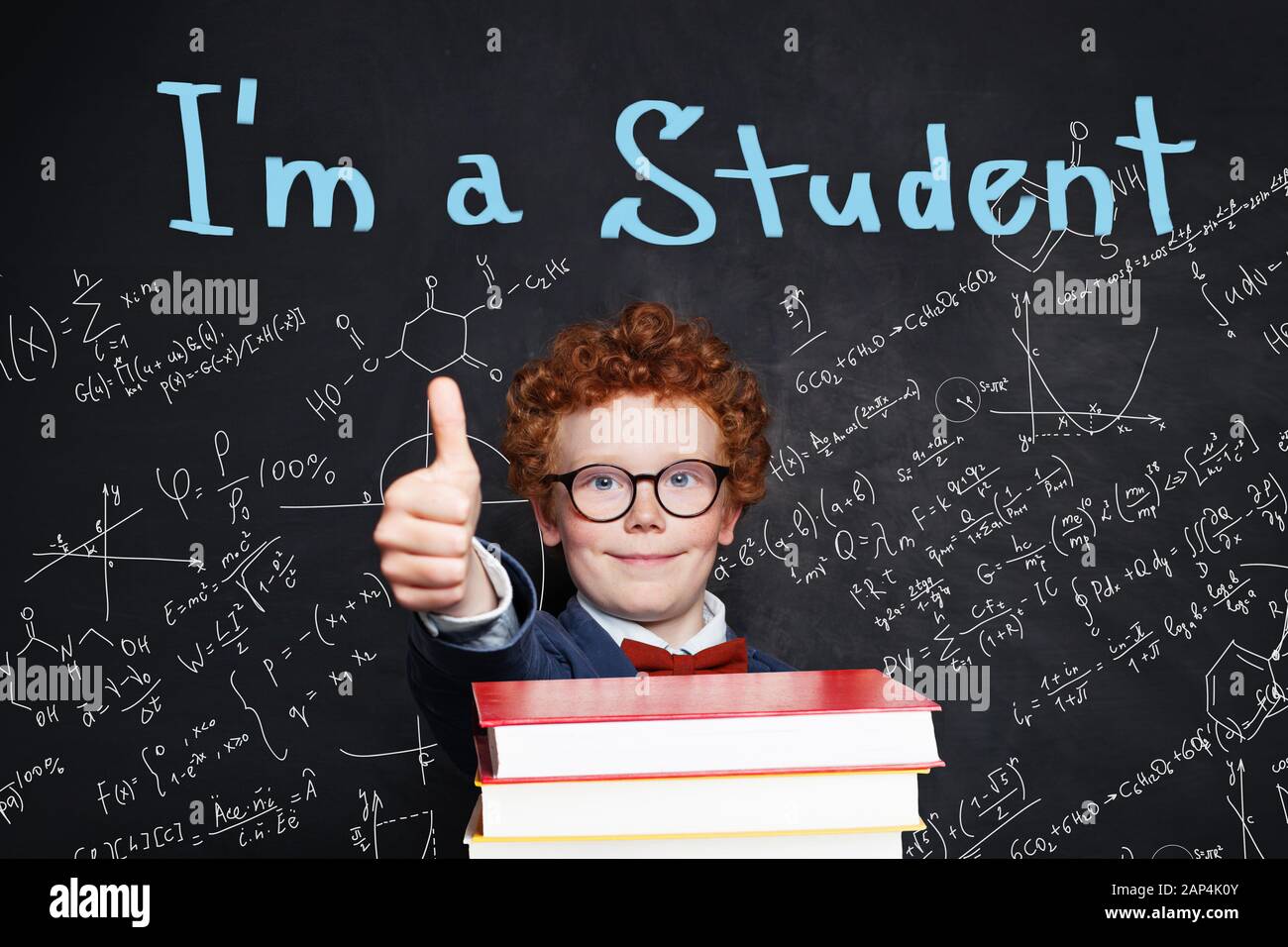 Kid school boy in student uniform holding books and showing thumb up, back to school concept Stock Photo