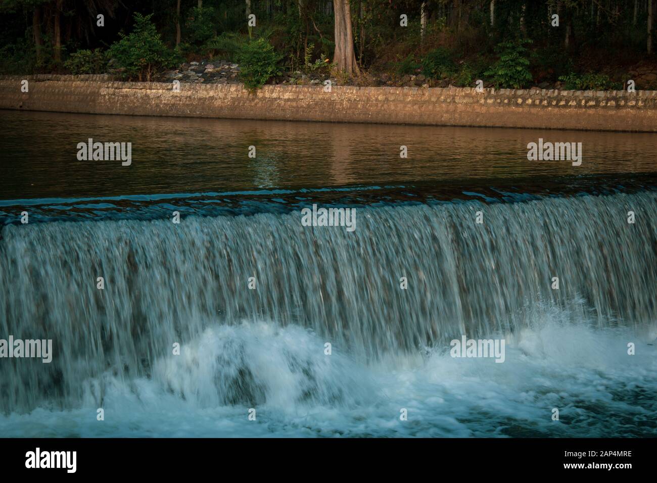 Close view of water flowing into Kaveri river through a canal from Krishna Raja Sagara dam, Mysore, Karnataka, India. Stream of water from canal flowi Stock Photo