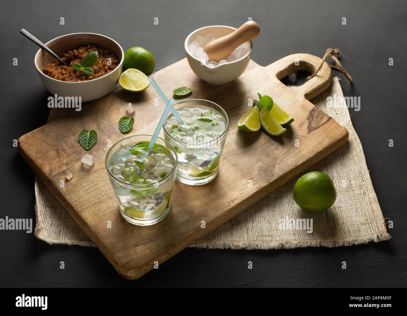 Caipirinha of Cachaça, Mojito of white rum, lime, fresh mint, brown sugar and crushed ice. Rustic environment with black background Stock Photo