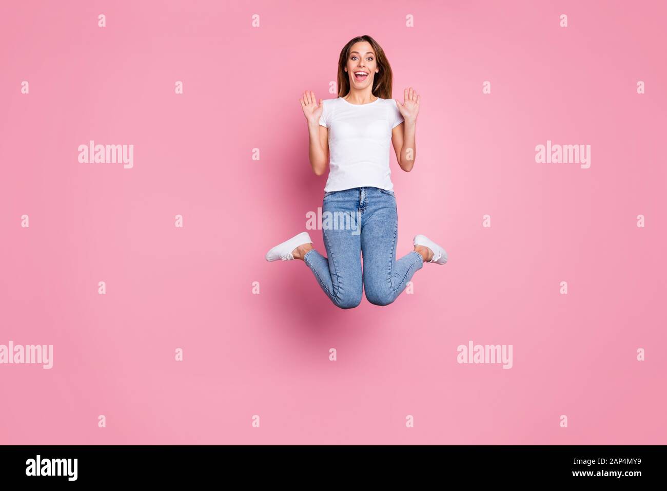 Photo of beautiful crazy lady jumping high enjoy summer sunny weekend days playful mood wear casual white t-shirt jeans sneakers isolated pink color Stock Photo