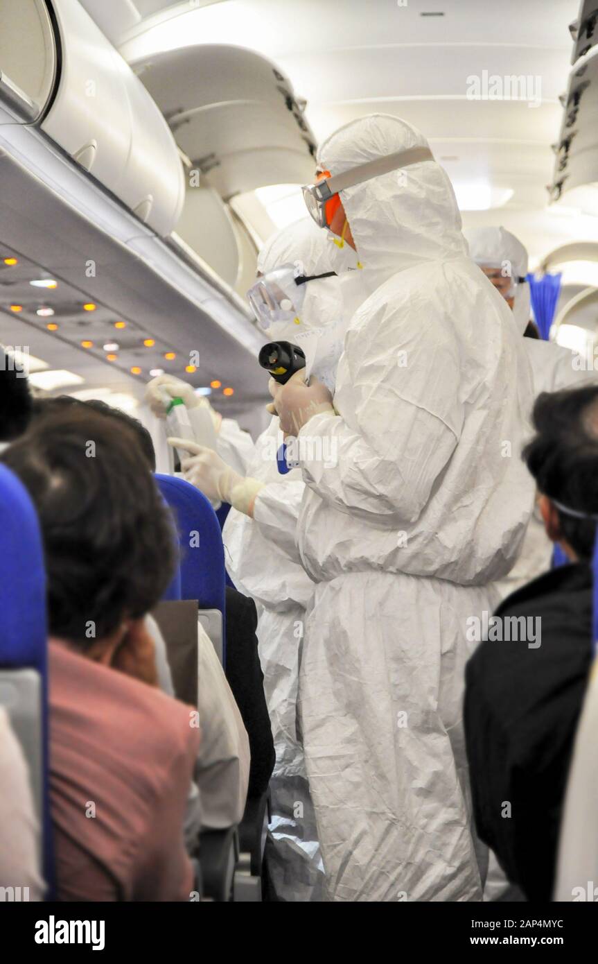 Medics in white hazmat protective suits checking and scanning passengers in a plane for epidemic virus symptoms. Chinese new Wuhan coronavirus illustr Stock Photo