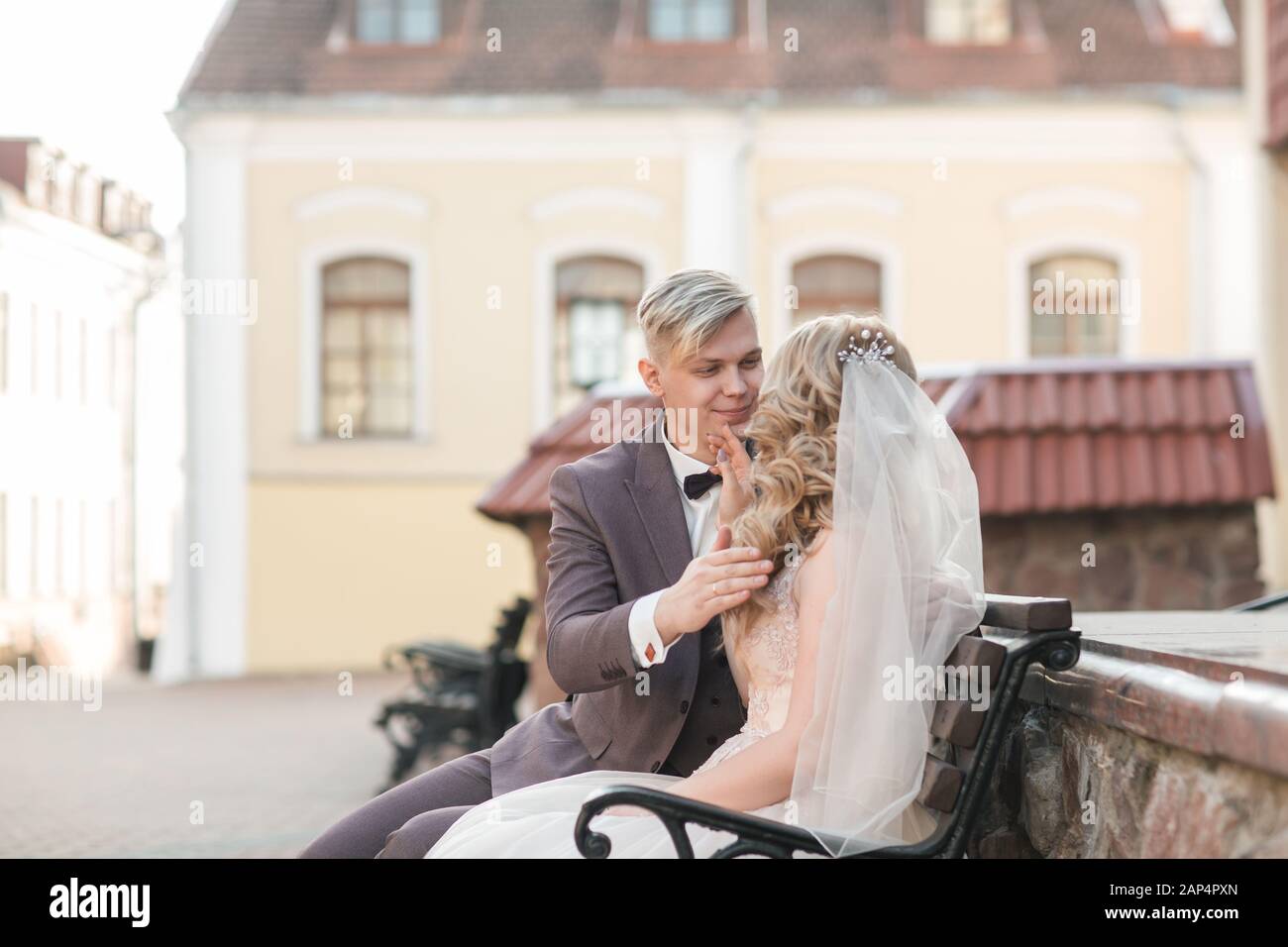 bride and groom sitting on a bench on a city street Stock Photo - Alamy
