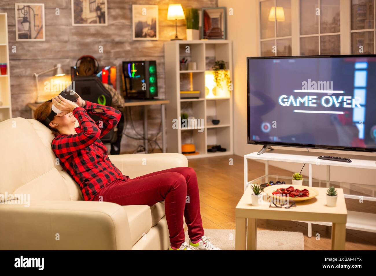 Woman losing at video games while playing using virtual reality headset late at night in the living room Stock Photo