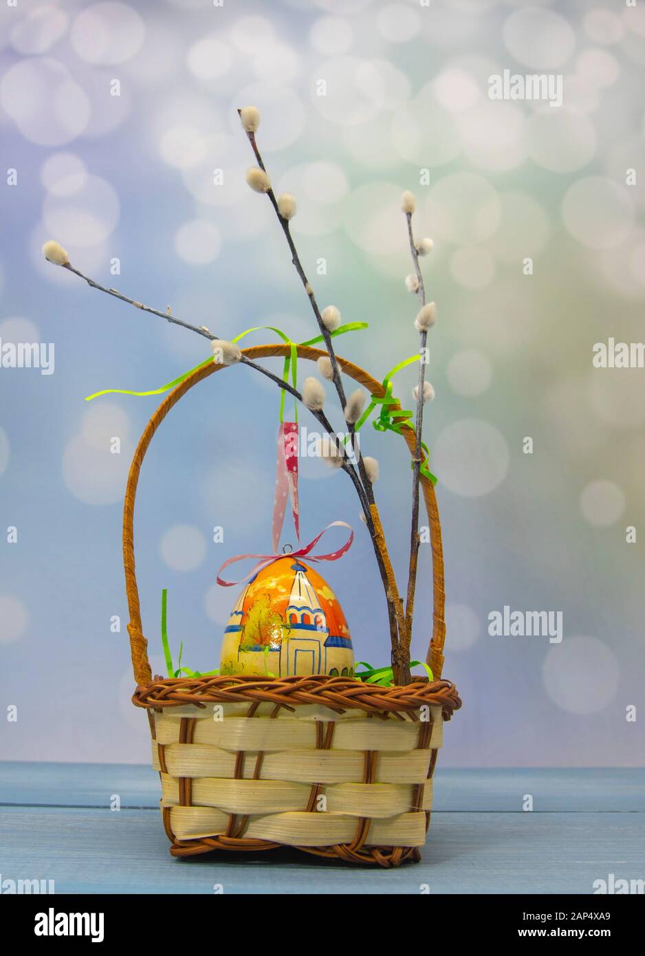 Wicker basket with one Easter egg and willow branches on a blurred ...