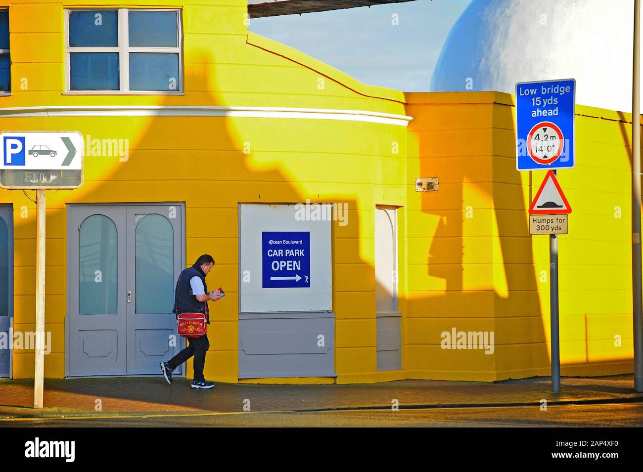 Man walking in front of yellow building on Ocean Boulevard between  traffic signs,Blackpool,Lancashire,UK Stock Photo