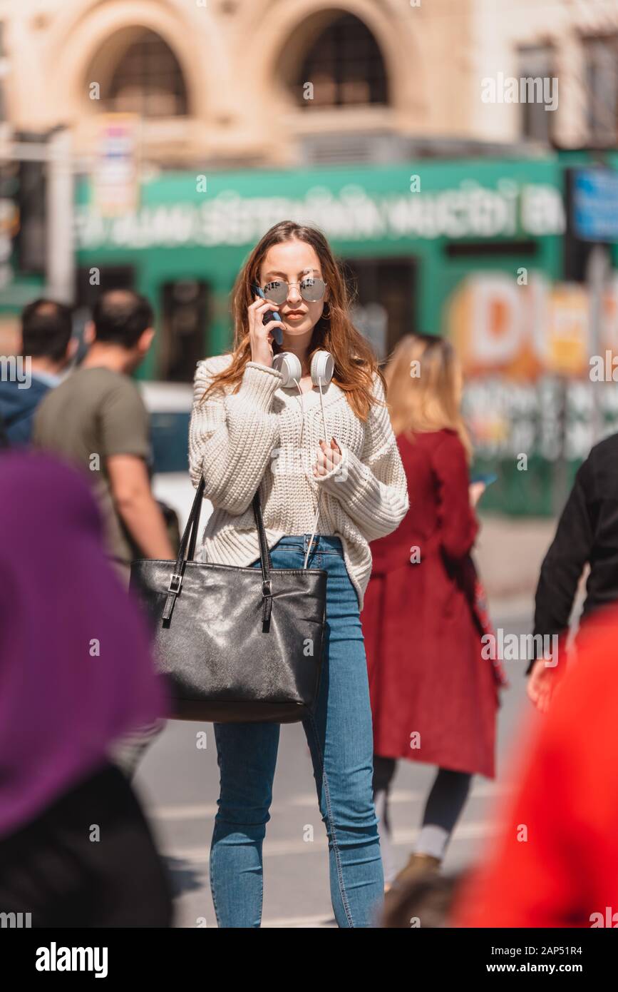 Beautiful attractive young girl in jumper and jeans with headphones and