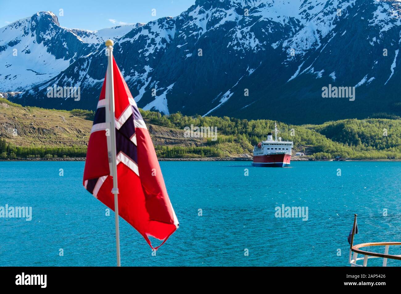 Norwegian flag with G Adventures cruise ship Expedition in Holandsfjorden fjord. Svartisen, Meløy municipality, Helgeland, Nordland, Norway Stock Photo