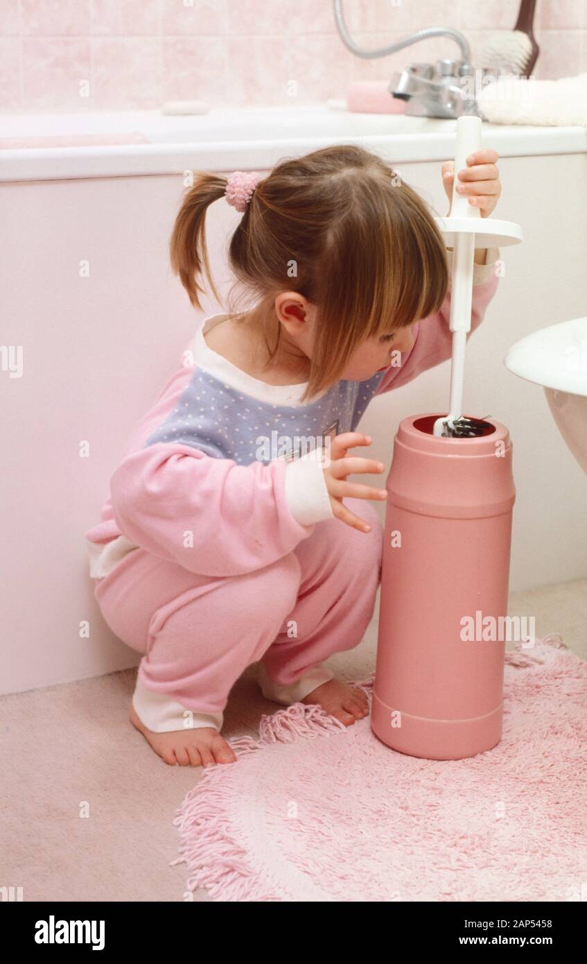 little girl in pyjamas playing with a toilet brush being unhygienic