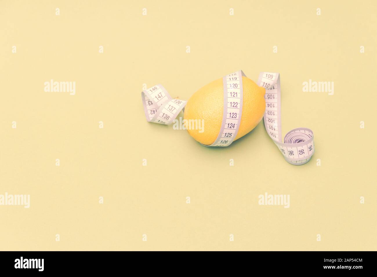 Lemon with measuring meter on yellow background. Healthy diet concept. Free copy space. Stock Photo