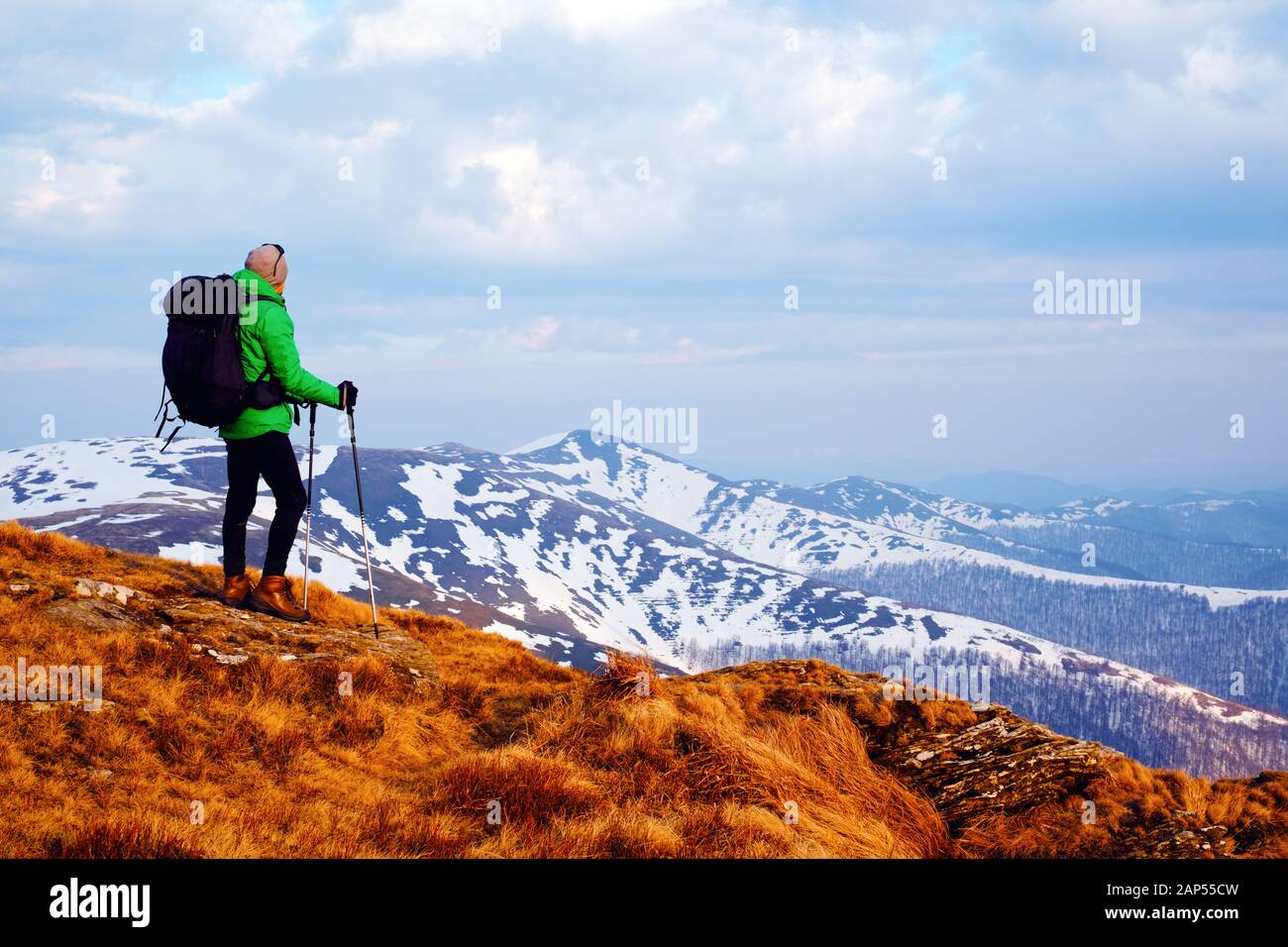 Amazing landscape with snowy mountains range and hiker with black backpack on a foreground Stock Photo