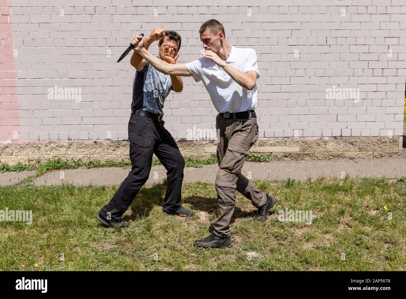 Mature male instructor blocks the hand of an attacker with a knife