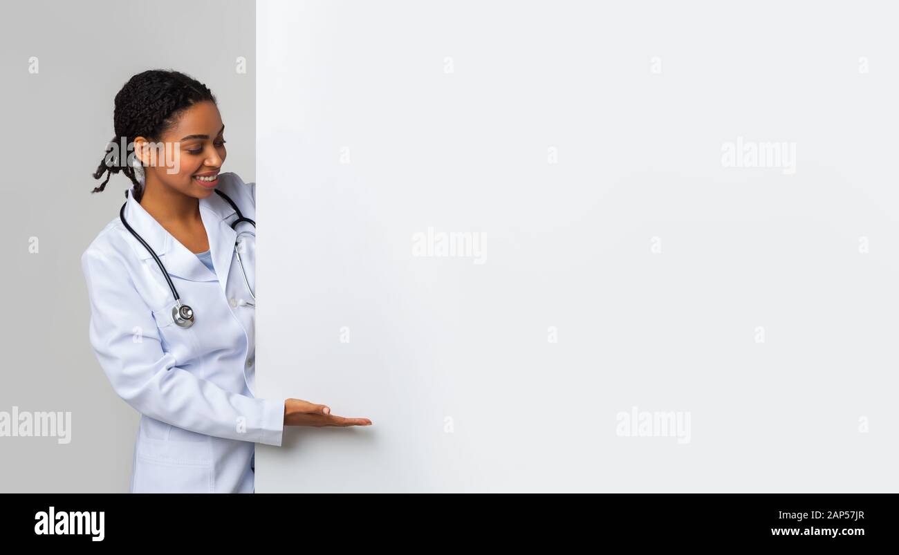 Black female doctor looking and pointing at big blank advertising board Stock Photo