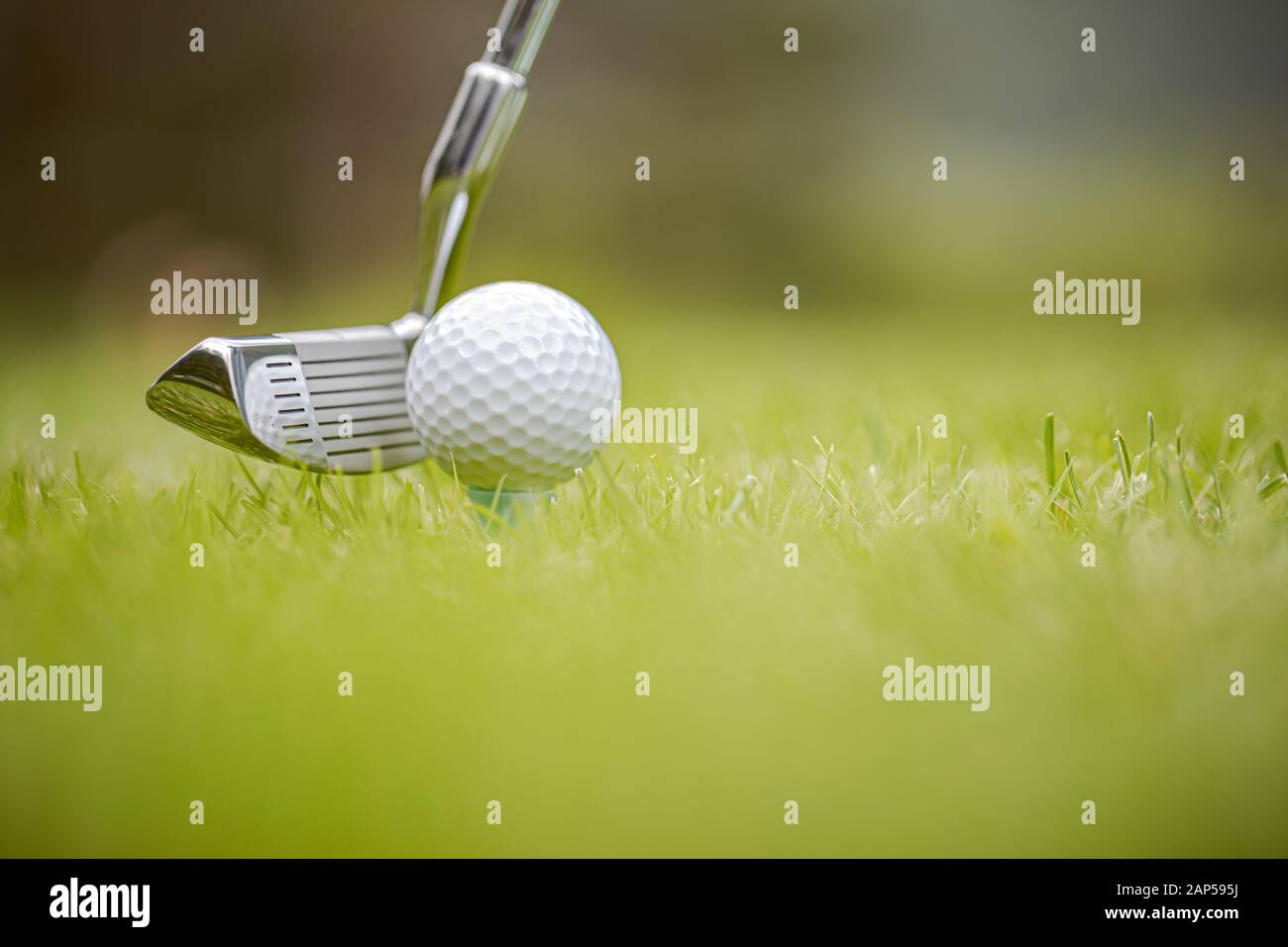 Golf club and ball on tee in front of driver Stock Photo