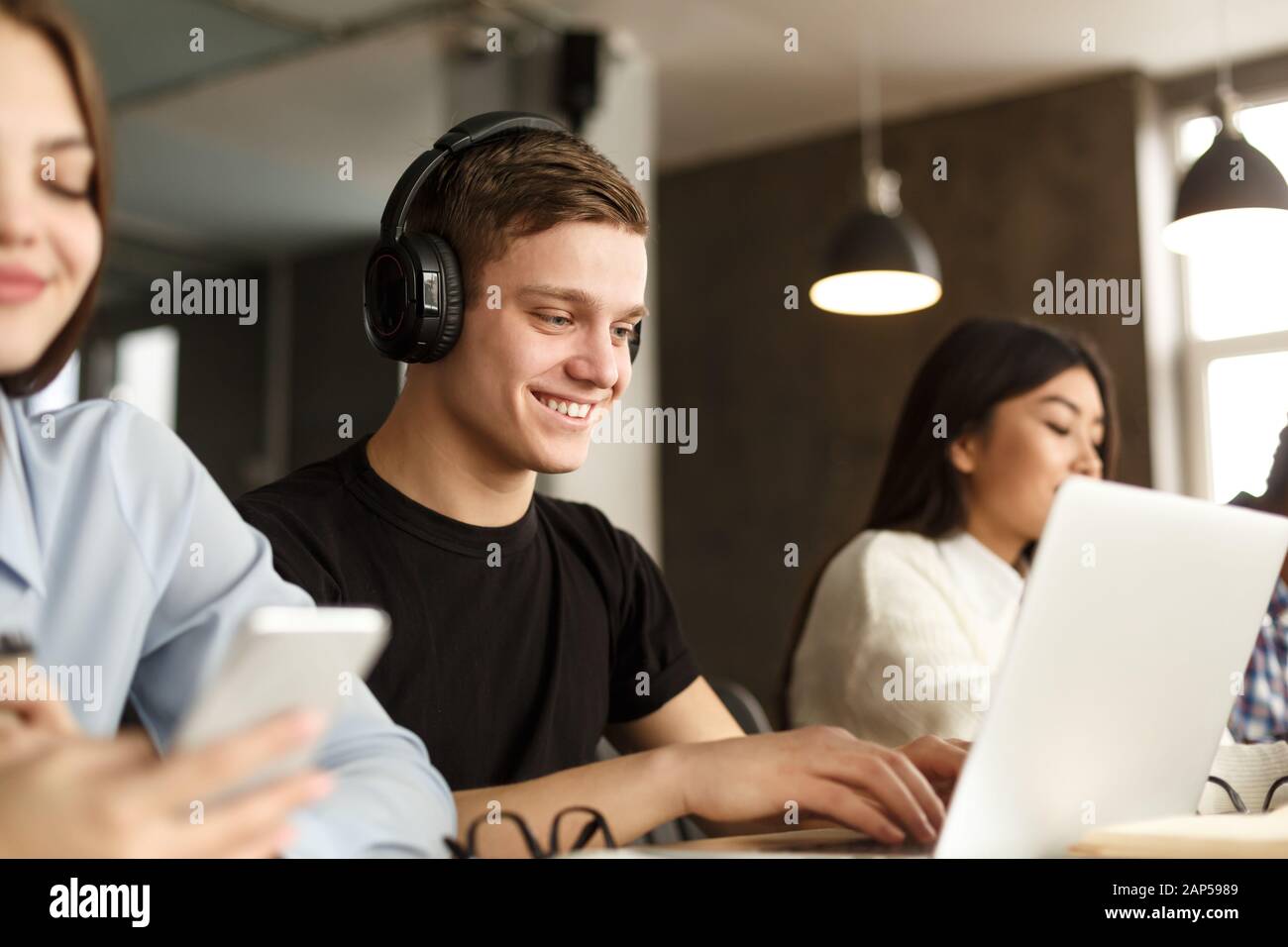 Smiling guy studying in college library, using laptop Stock Photo