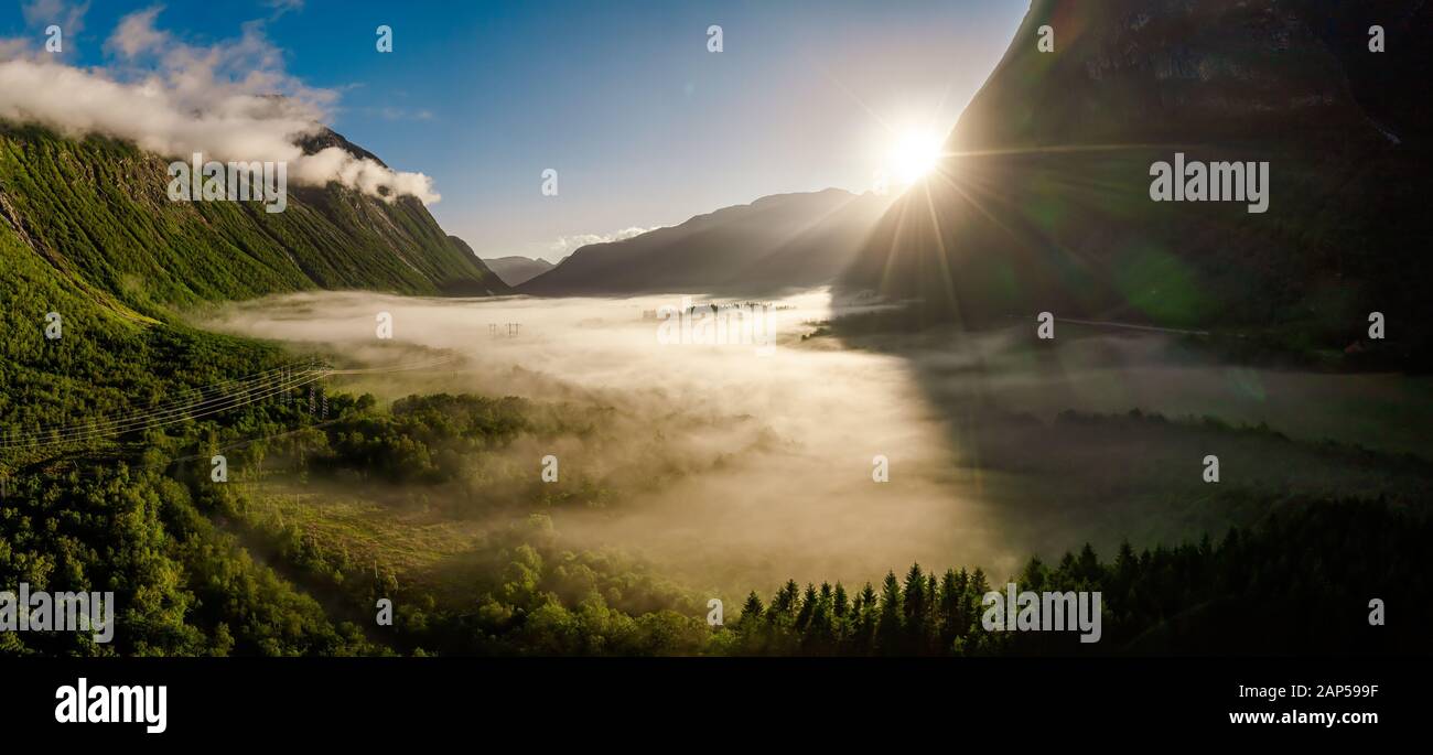 Morning mist over the valley among the mountains in the sunlight. Fog and Beautiful nature of Norway aerial footage. Stock Photo