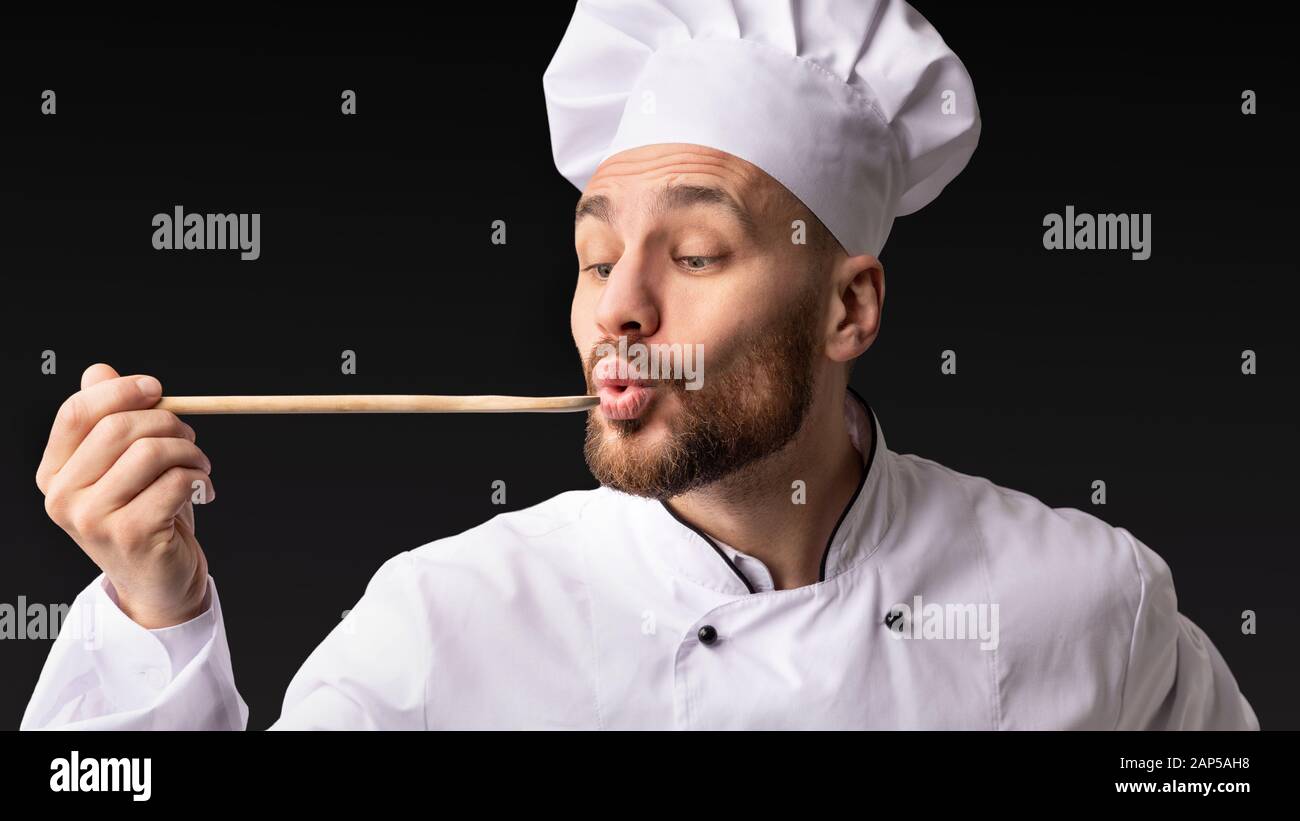 https://c8.alamy.com/comp/2AP5AH8/chef-man-holding-spoon-tasting-food-on-black-background-panorama-2AP5AH8.jpg
