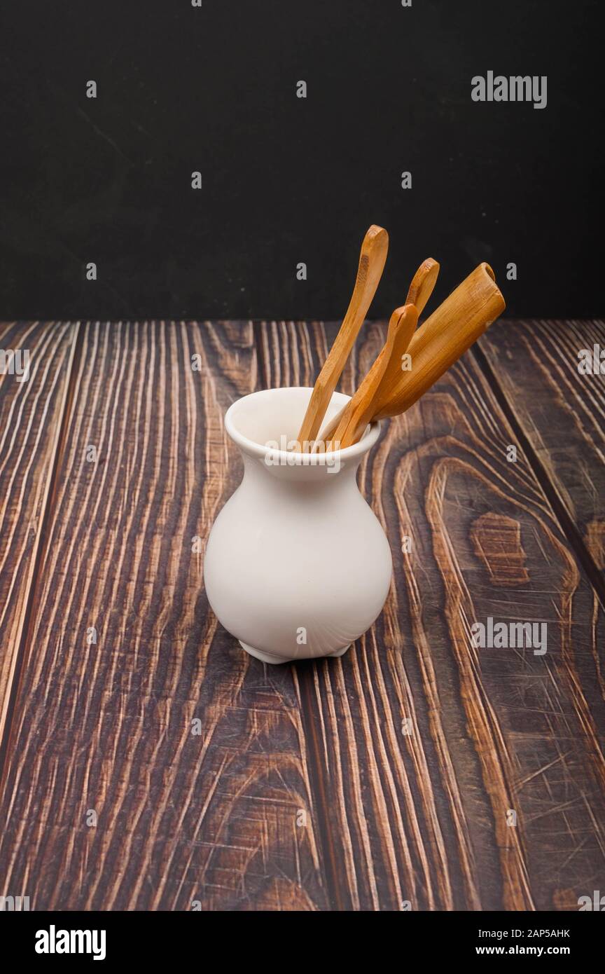 Devices for traditional Chinese tea drinking made of bamboo in a white ceramic vase in the Chinese style on a wooden background. Close up Stock Photo