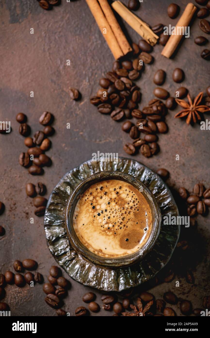 Black coffee espresso with foam in black ceramic cup, with saucer