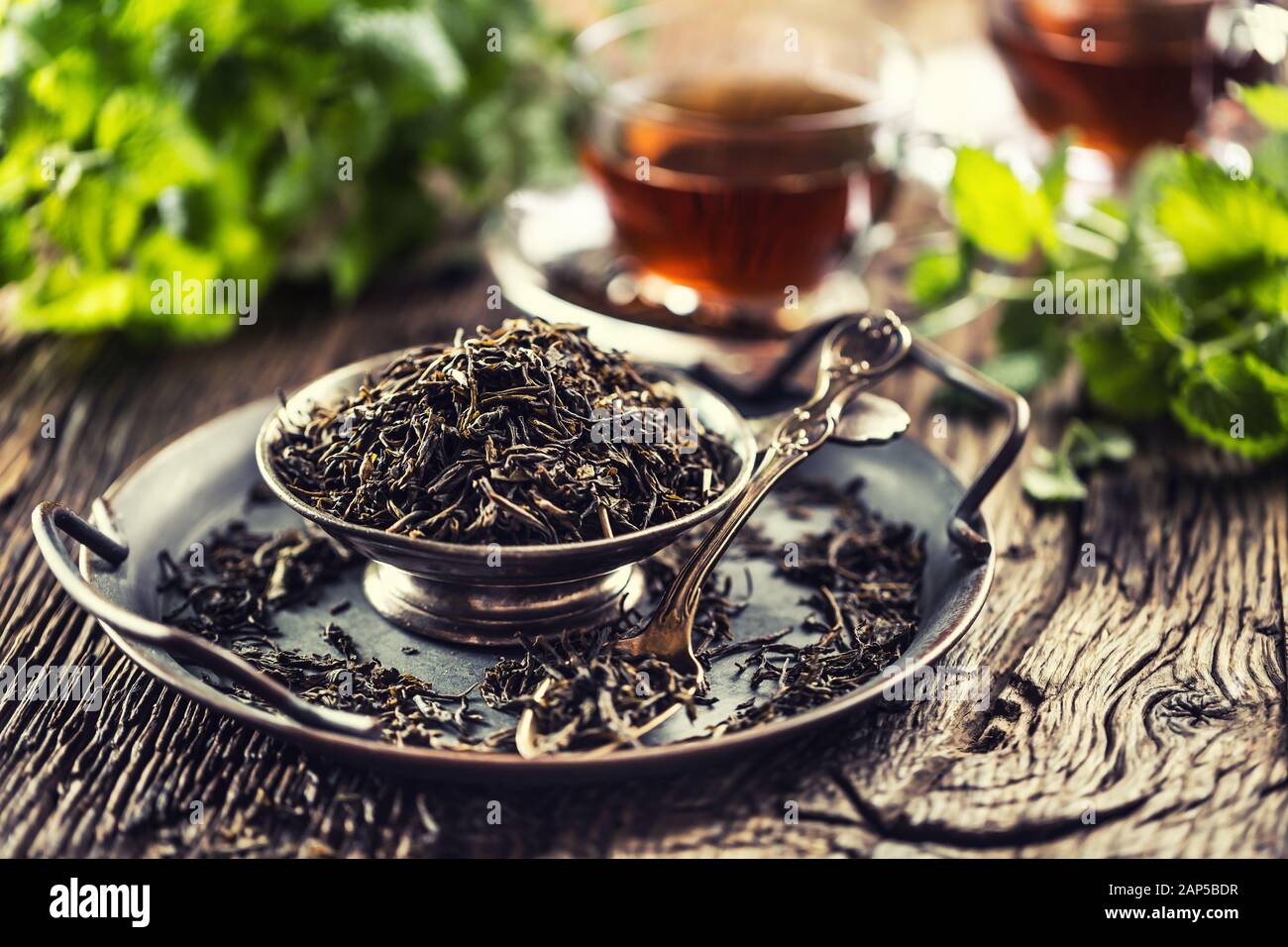 Dried tea leaves in bowl on rustic wooden table Stock Photo