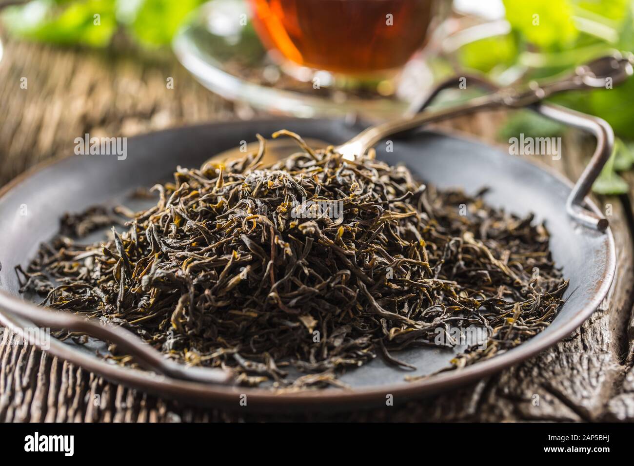 Dried tea leaves in bowl on rustic wooden table Stock Photo