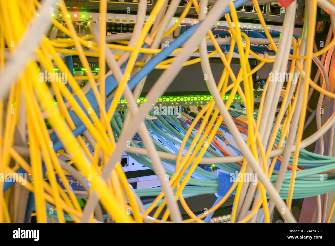 Chaotic intertwining of many Internet wires in the rack server room. Messy Communication cables are in the datacenter. Patch panel cabinet with comput Stock Photo