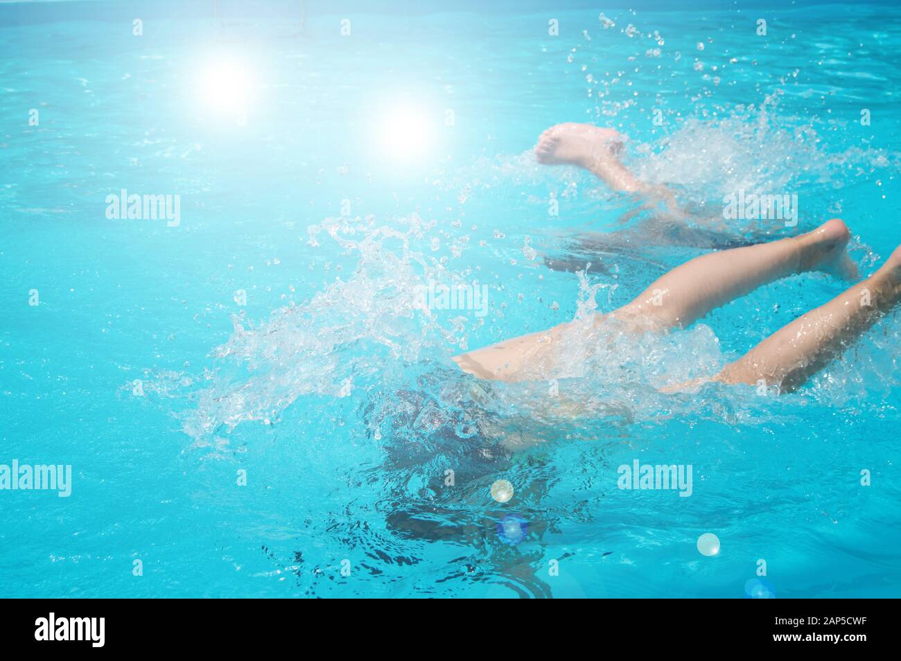 Children teenagers girls have fun swimming and diving in the outdoor pool, feet up over the water, splashing, sunlight, glare, summer day Stock Photo