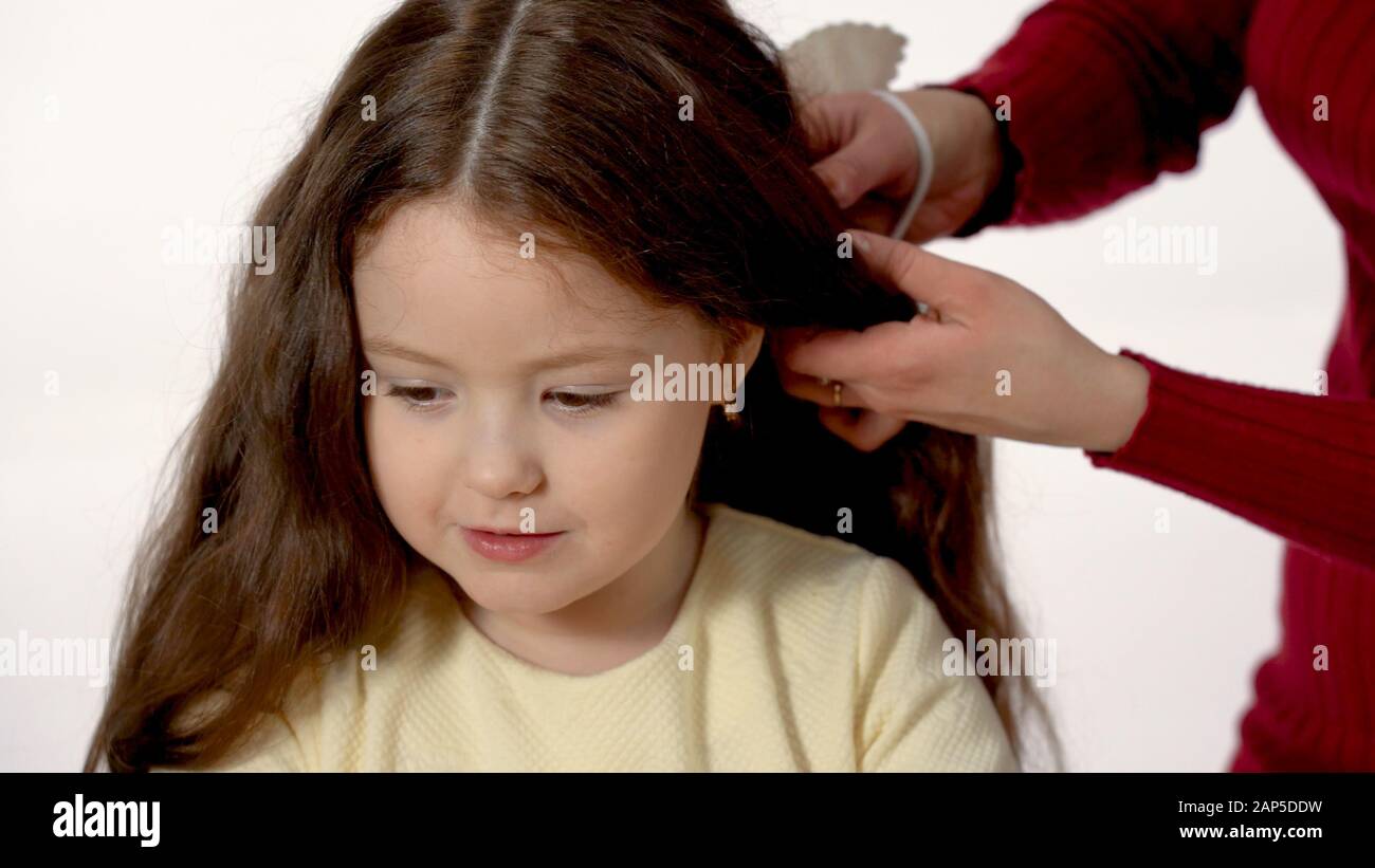 Mom Braids The Braid Of Her Daughter With Long Hair Separately On