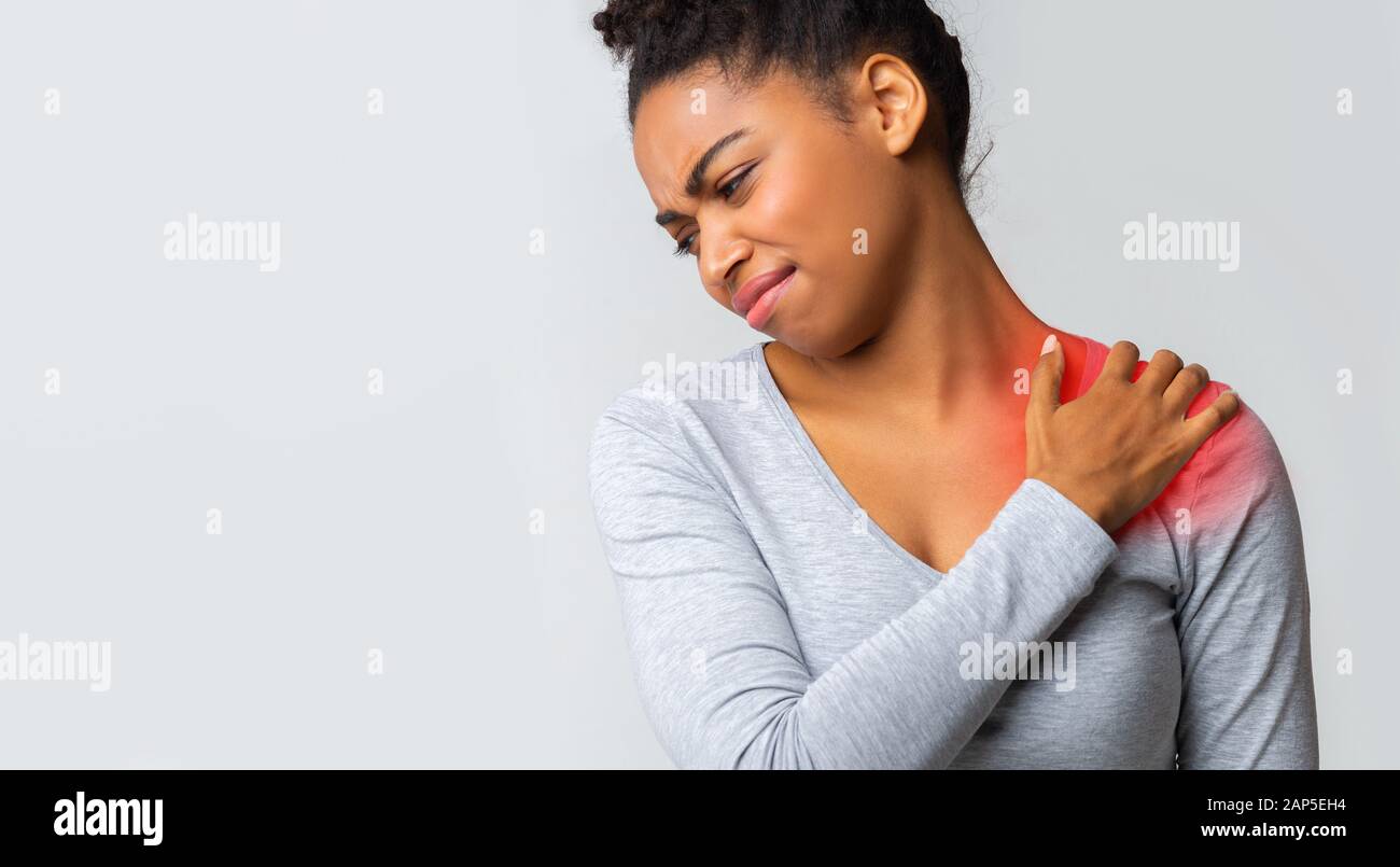Sad girl having strong pain in shoulder, massaging painful zone Stock Photo