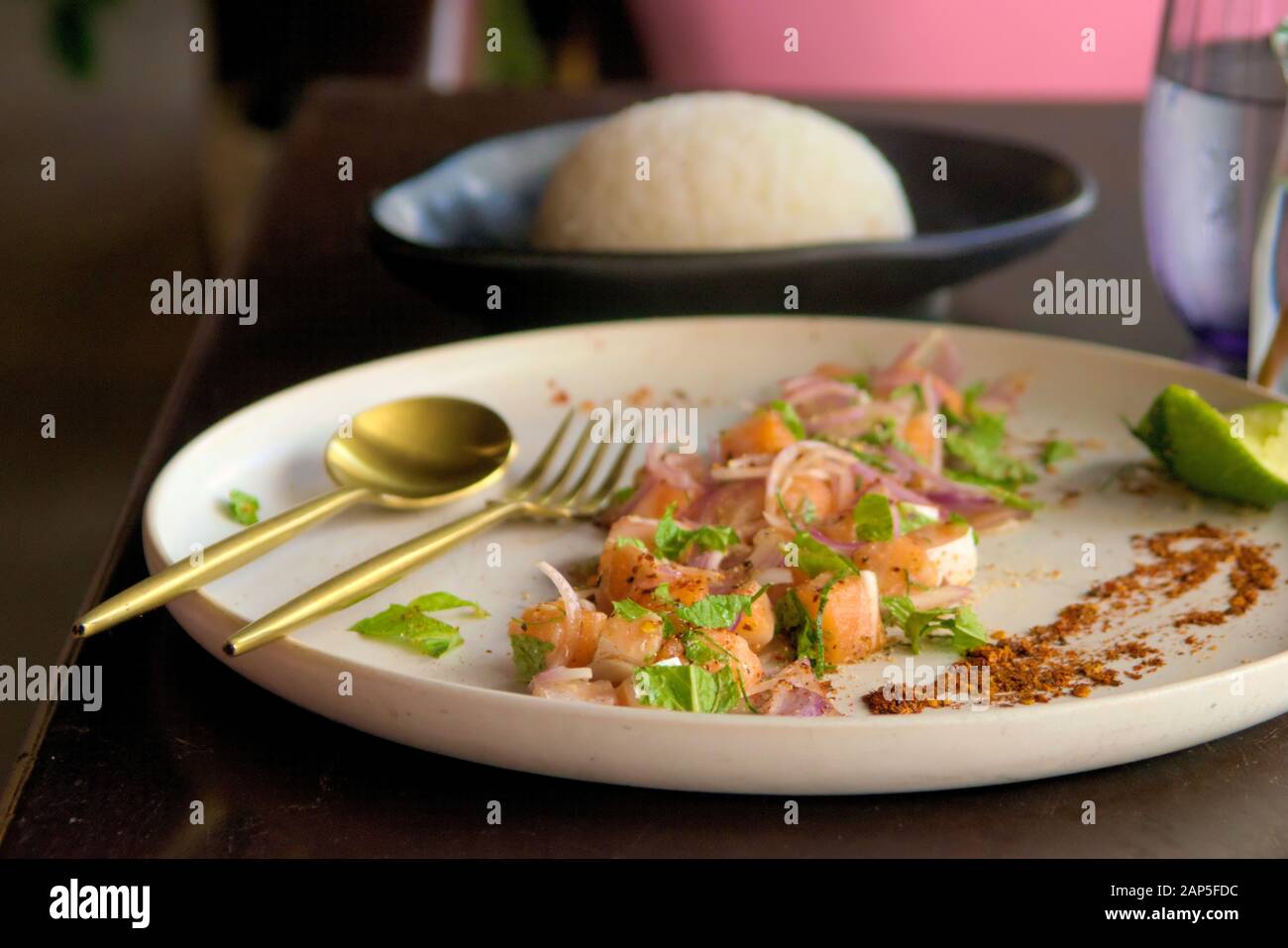 Diced raw salmon with red onions, lemon and mint, with steamed rice on the side. Close up shot. Stock Photo